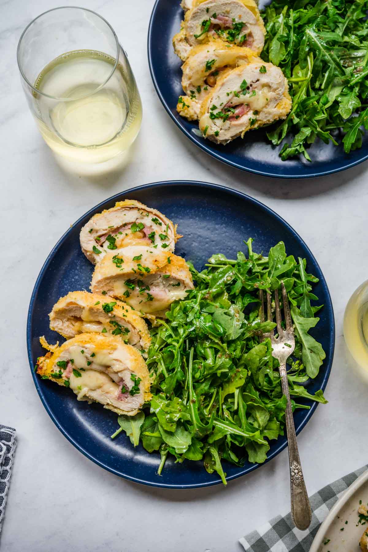 Chicken Cordon Bleu sliced for serving on plate with salad