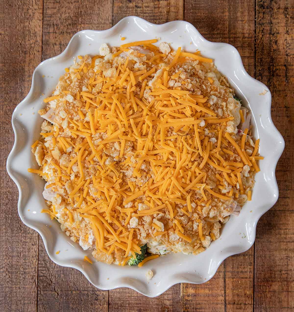 Chicken Divan in pie plate covered with cheese before baking