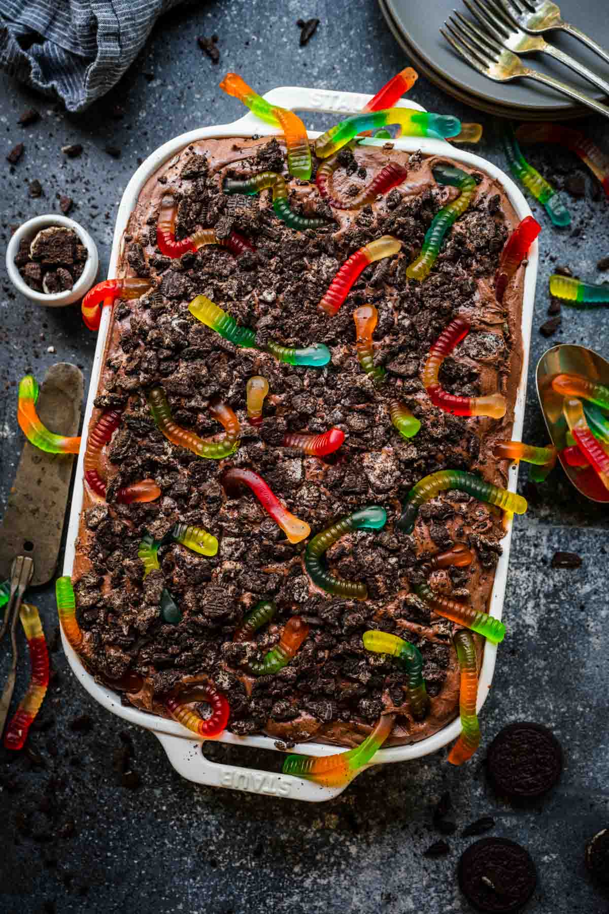 Chocolate Pudding Dirt Cake with pudding, crushed oreos, and gummy worms on top in baking dish