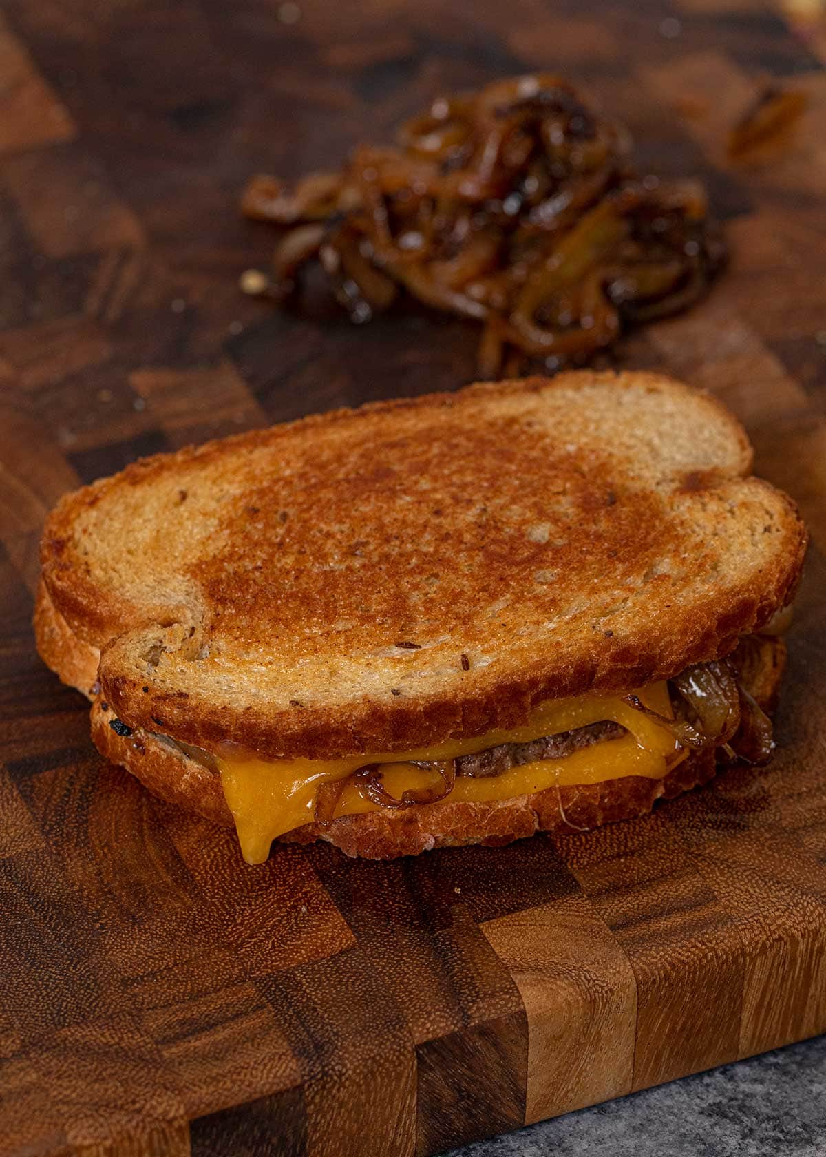 Classic Patty Melt on cutting board with caramelized onions