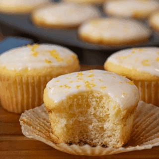 lemon muffin with some in the background and a baking tin of them farther in the background