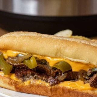 cooked seasoned meat with some dairy and veggies in between two buns