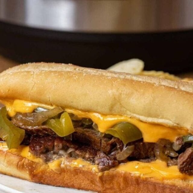 cooked seasoned meat with some dairy and veggies in between two buns