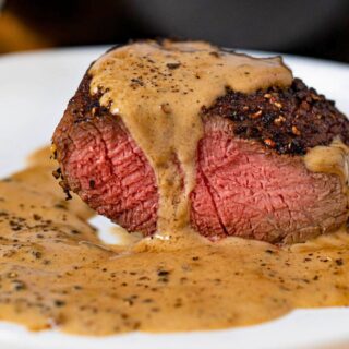 Plated cooked steak topped with sauce.