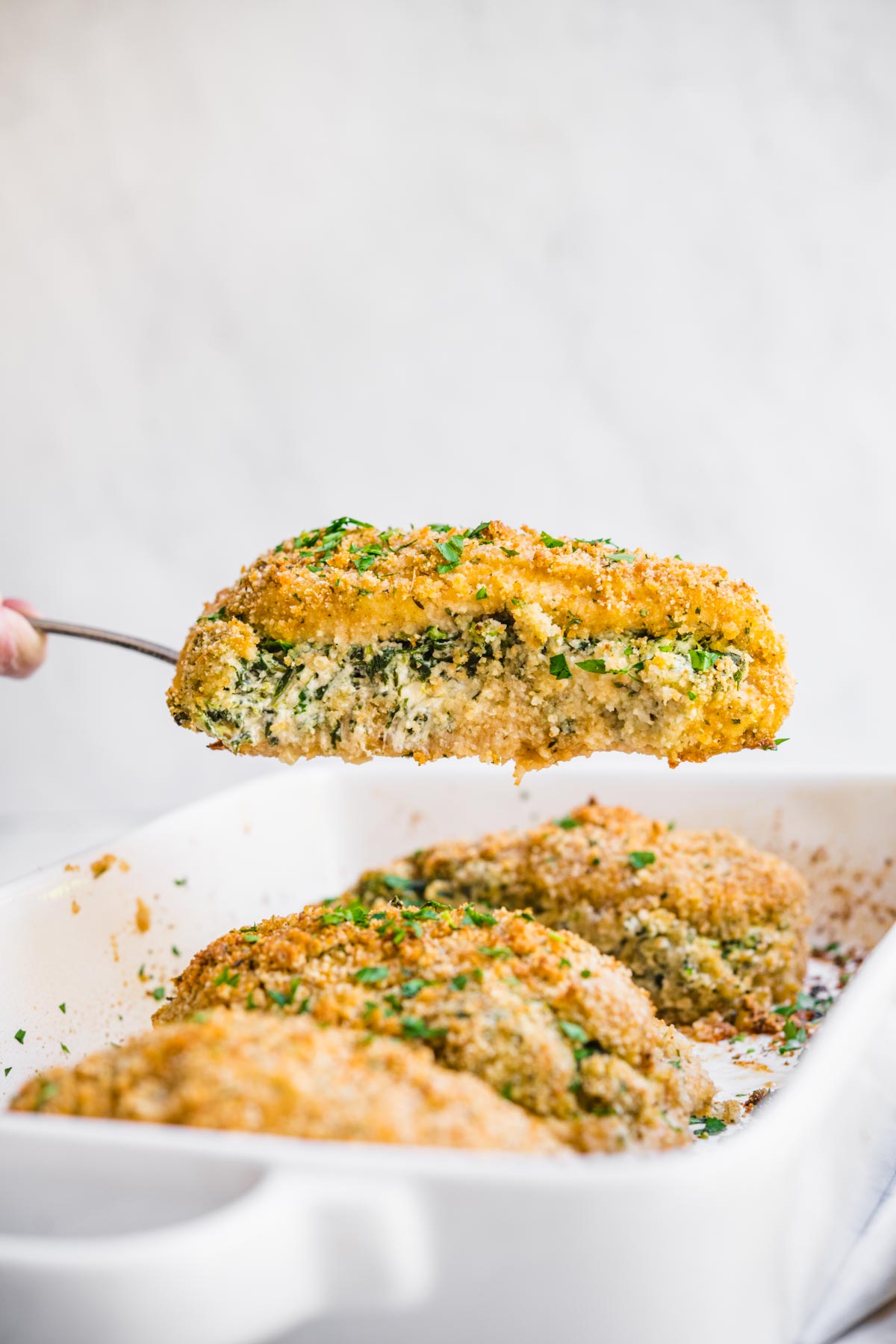 Stuffed Chicken Breast in baking dish with spatula