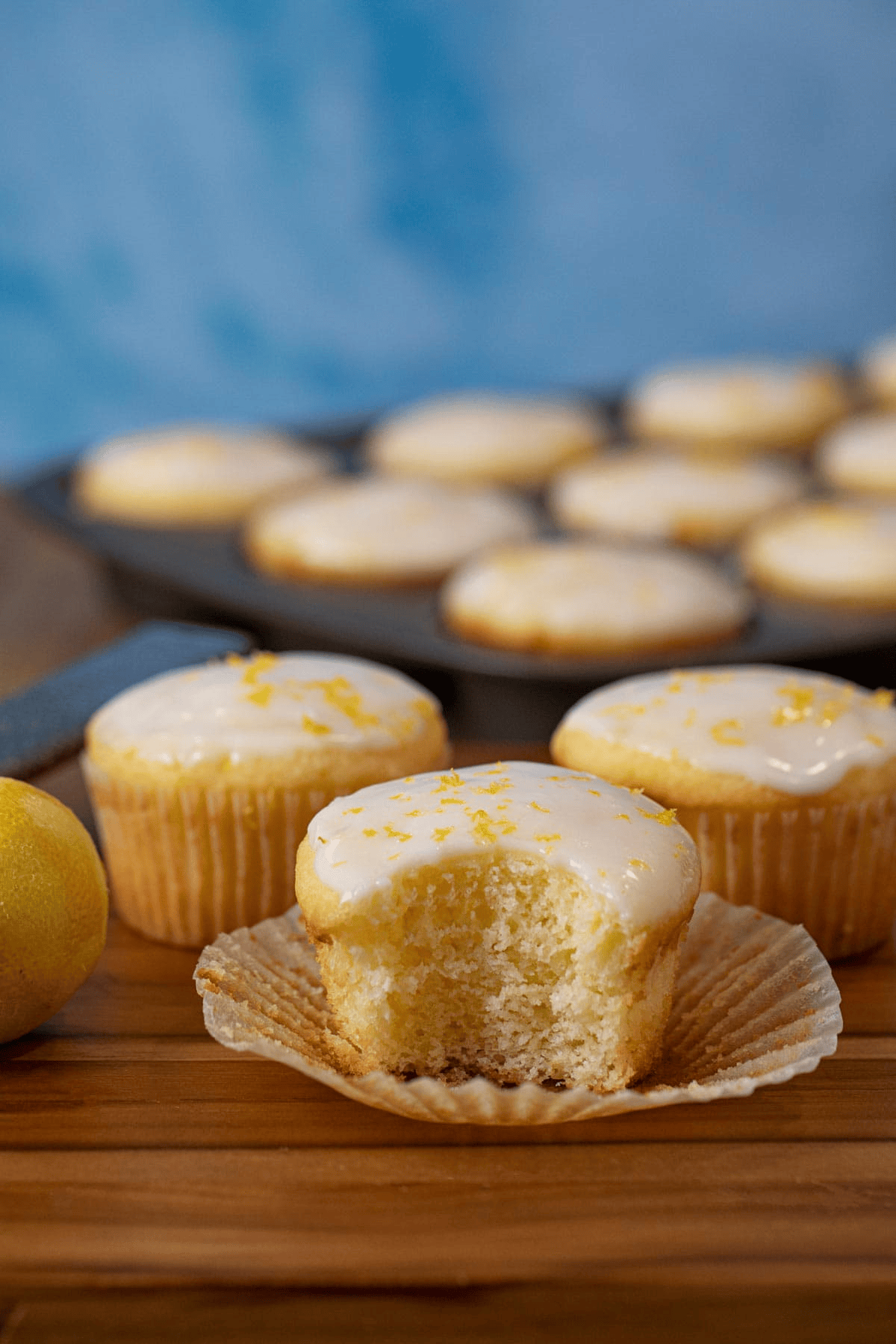 Baking tin of muffins with three in front and one with a bite out