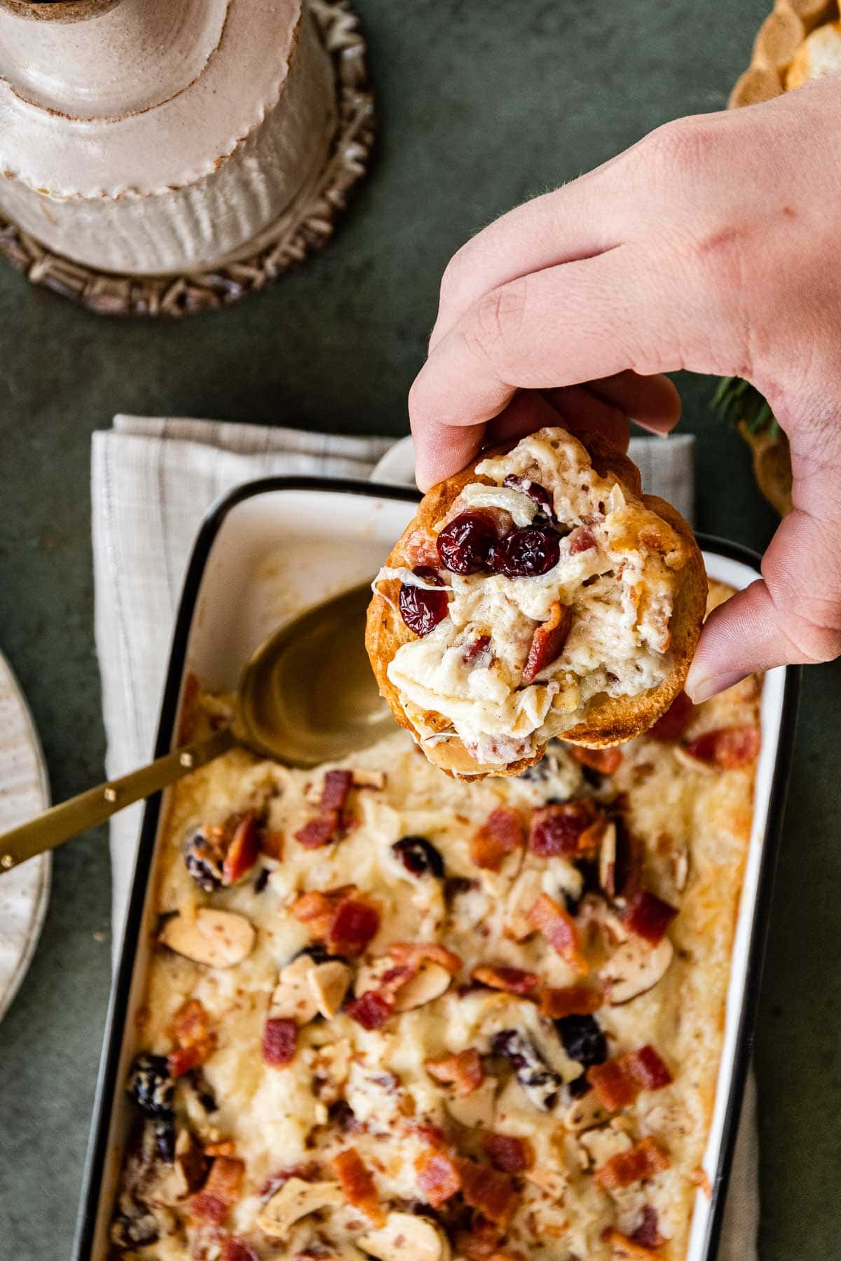 Bacon Cranberry Swiss Cheese Dip in baking dish with spoon and french bread slice