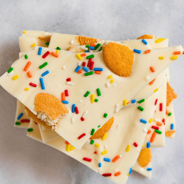 top view of white chocolate pieces with rainbow sprinkles and broken cookies on top