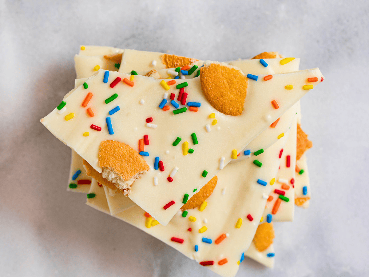 top view of white chocolate pieces with rainbow sprinkles and broken cookies on top
