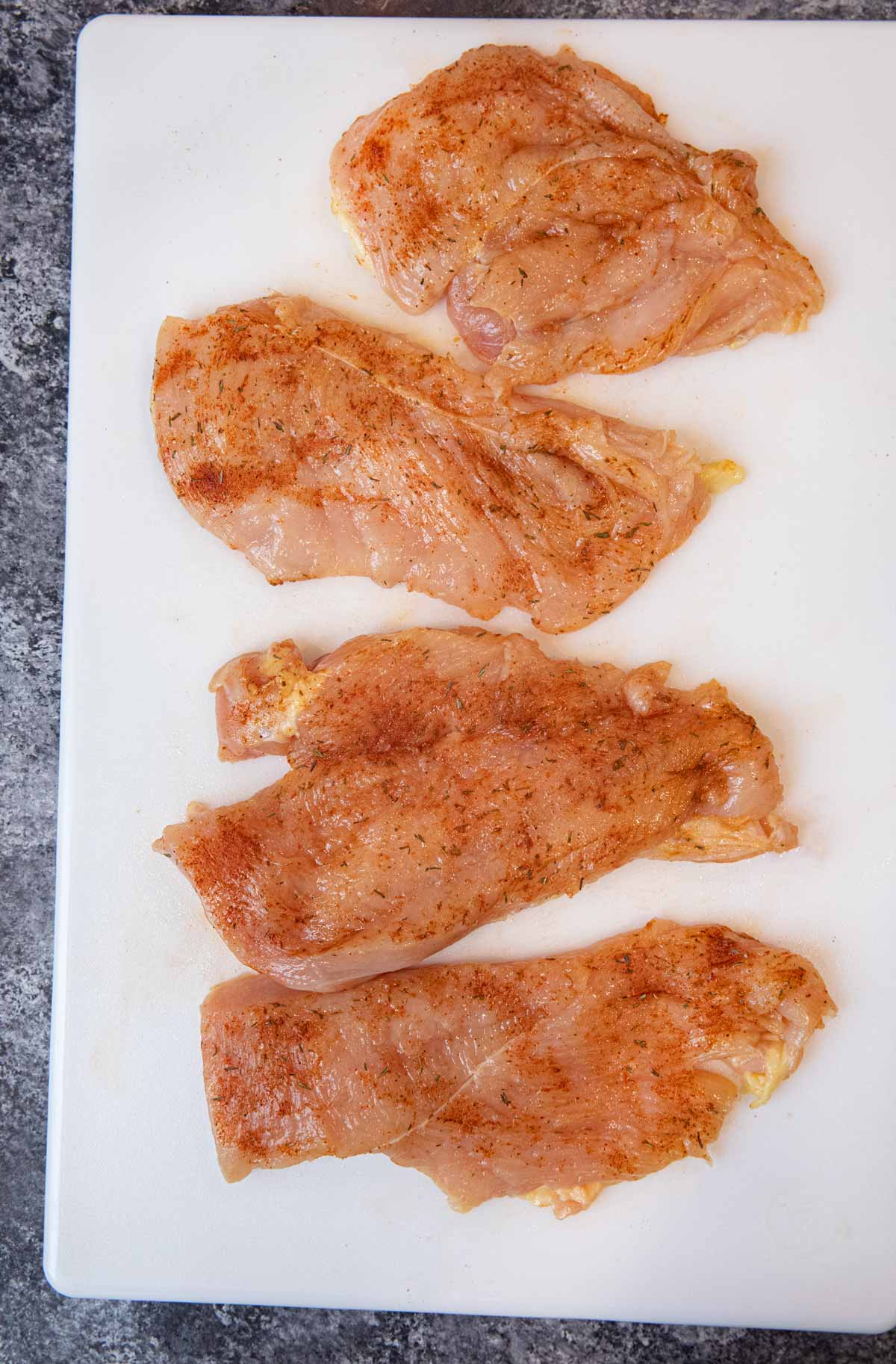 Blackened Chicken raw chicken breast coated with rub on cutting board