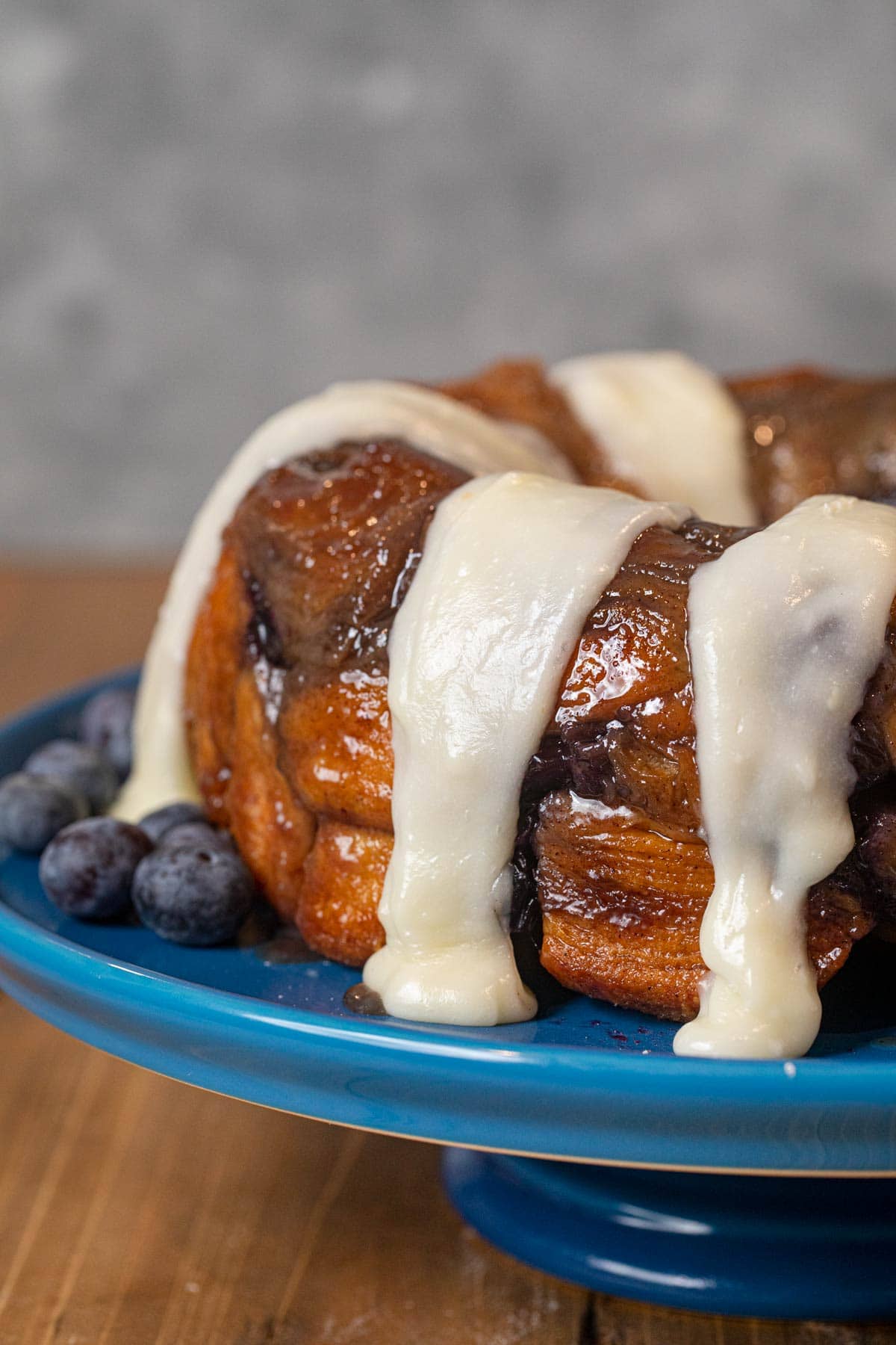 Blueberry Cream Cheese Monkey Bread on cake stand with icing