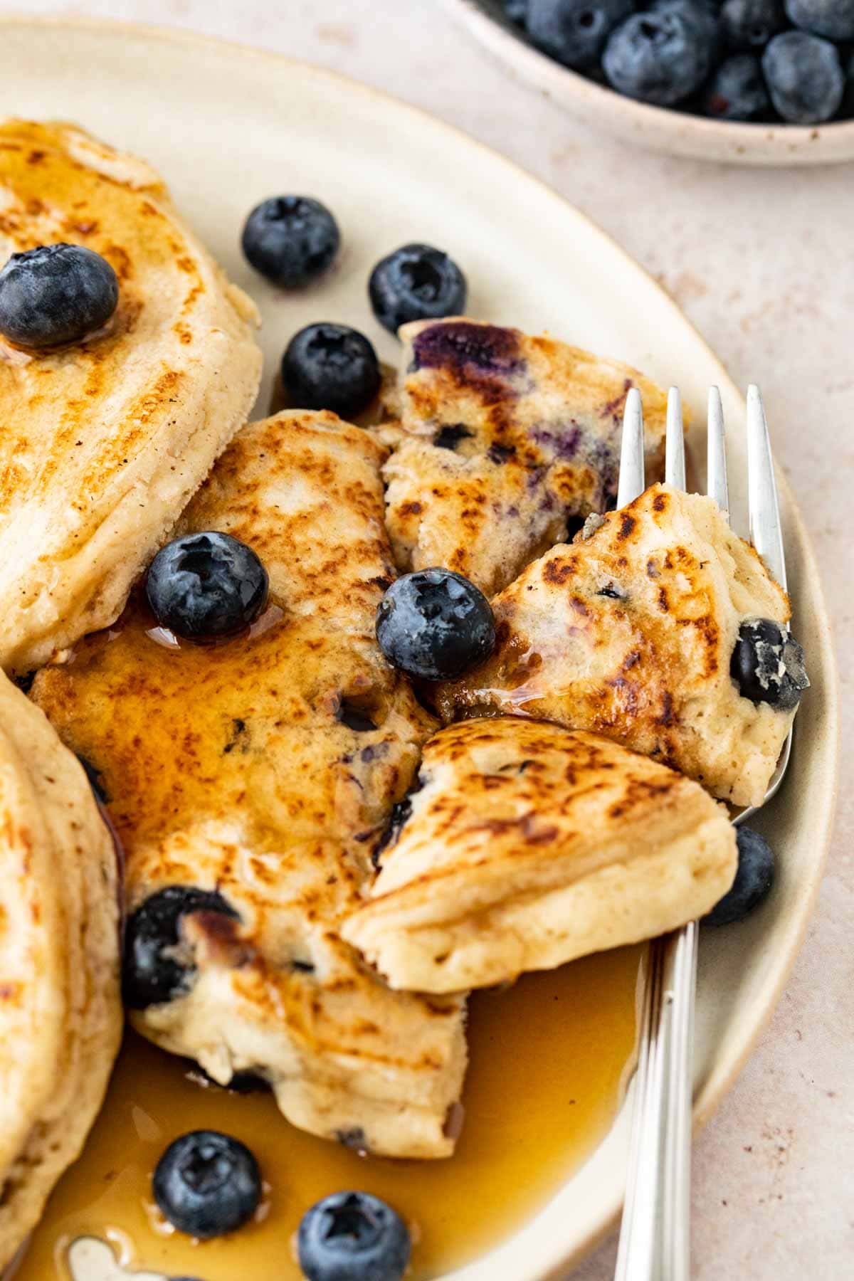 Blueberry Pancakes on plate with syrup cut up with fork