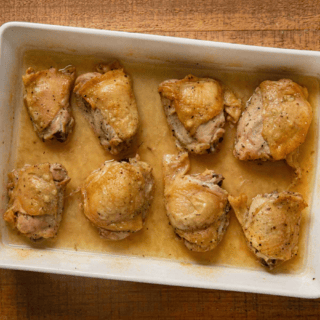 8 pieces of Poultry in a white baking dish in a light colored sauce