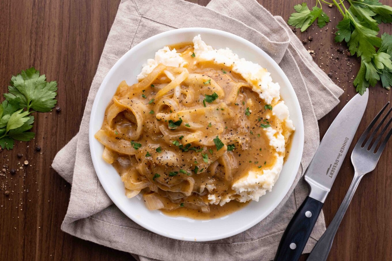 cube steak with gravy on white plate with knife and fork