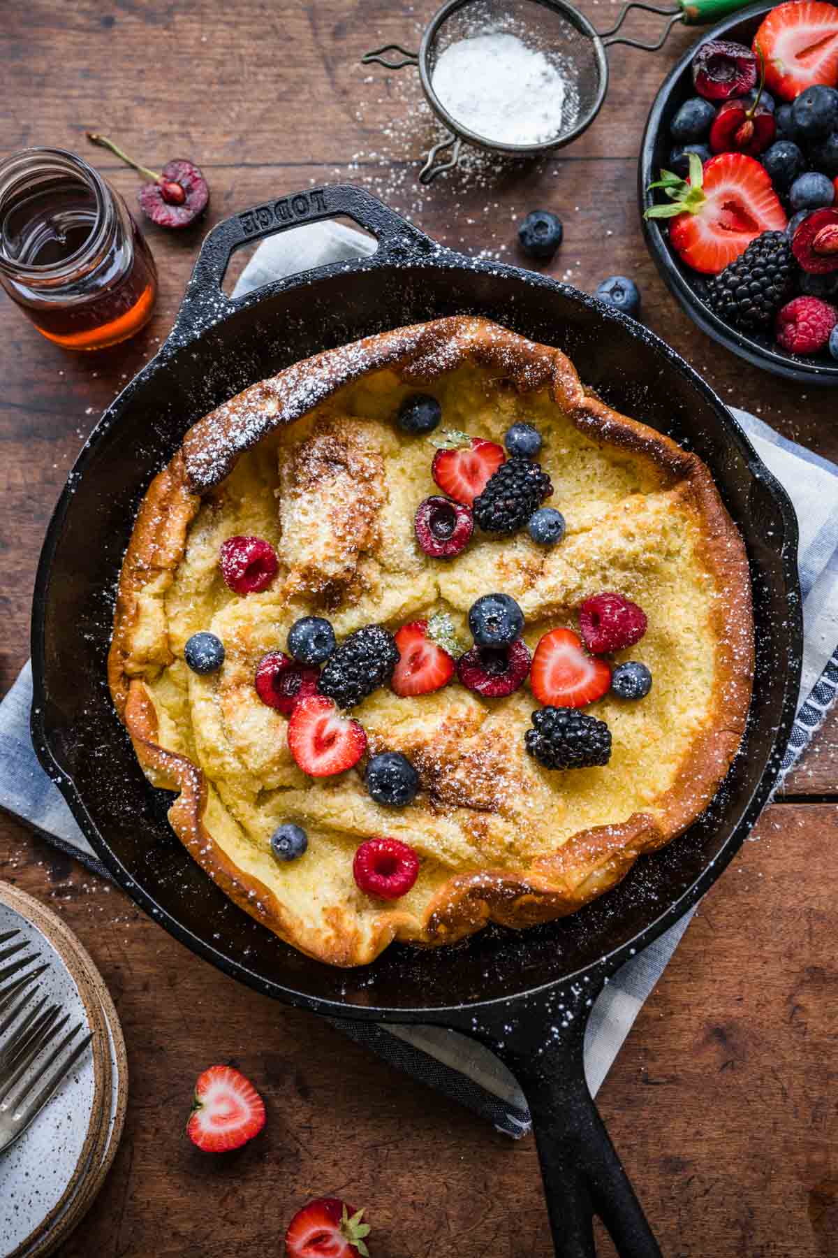 Skillet Baked Pancake in cast iron skillet with fresh berries and maple syrup