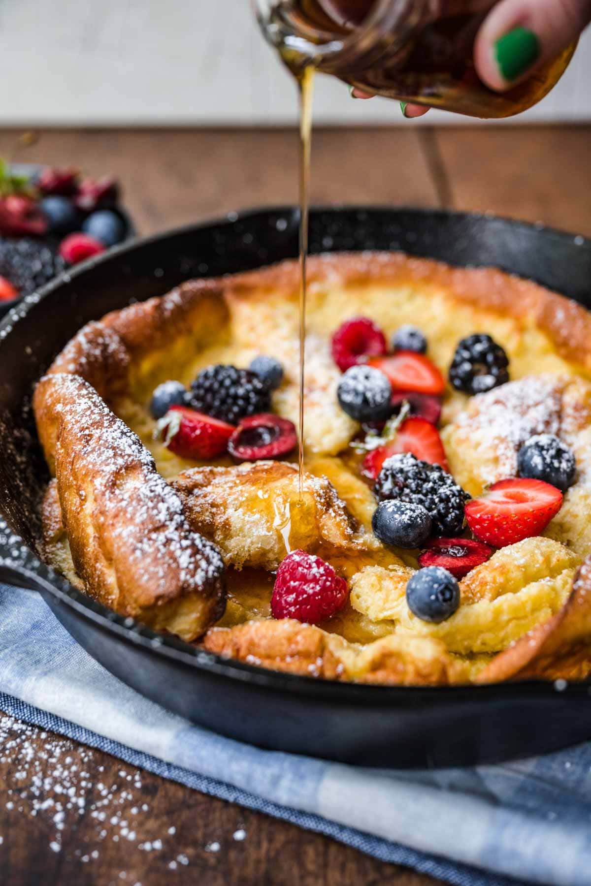 Skillet Baked Pancake in cast iron skillet with fresh berries and maple syrup