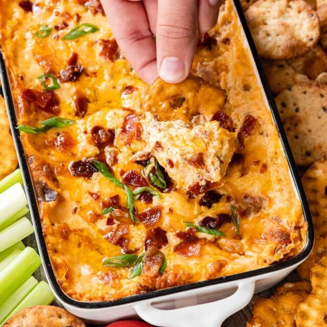 Hot Bacon Cheese Dip in baking dish with crackers and veggies