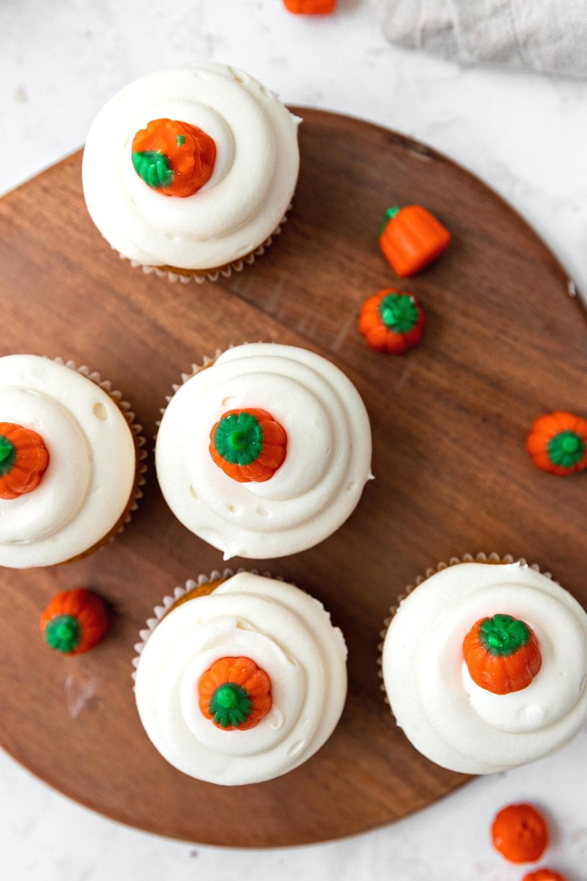 Pumpkin Cupcakes frosted with pumpkin candy on top, top view on cutting board