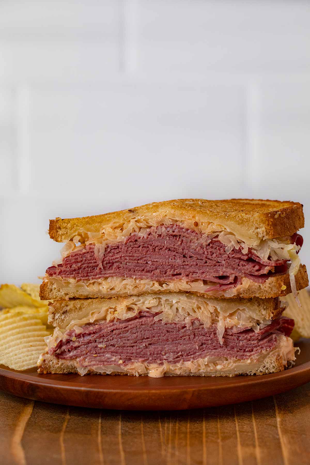 Reuben Sandwich halves in stack on plate with chips