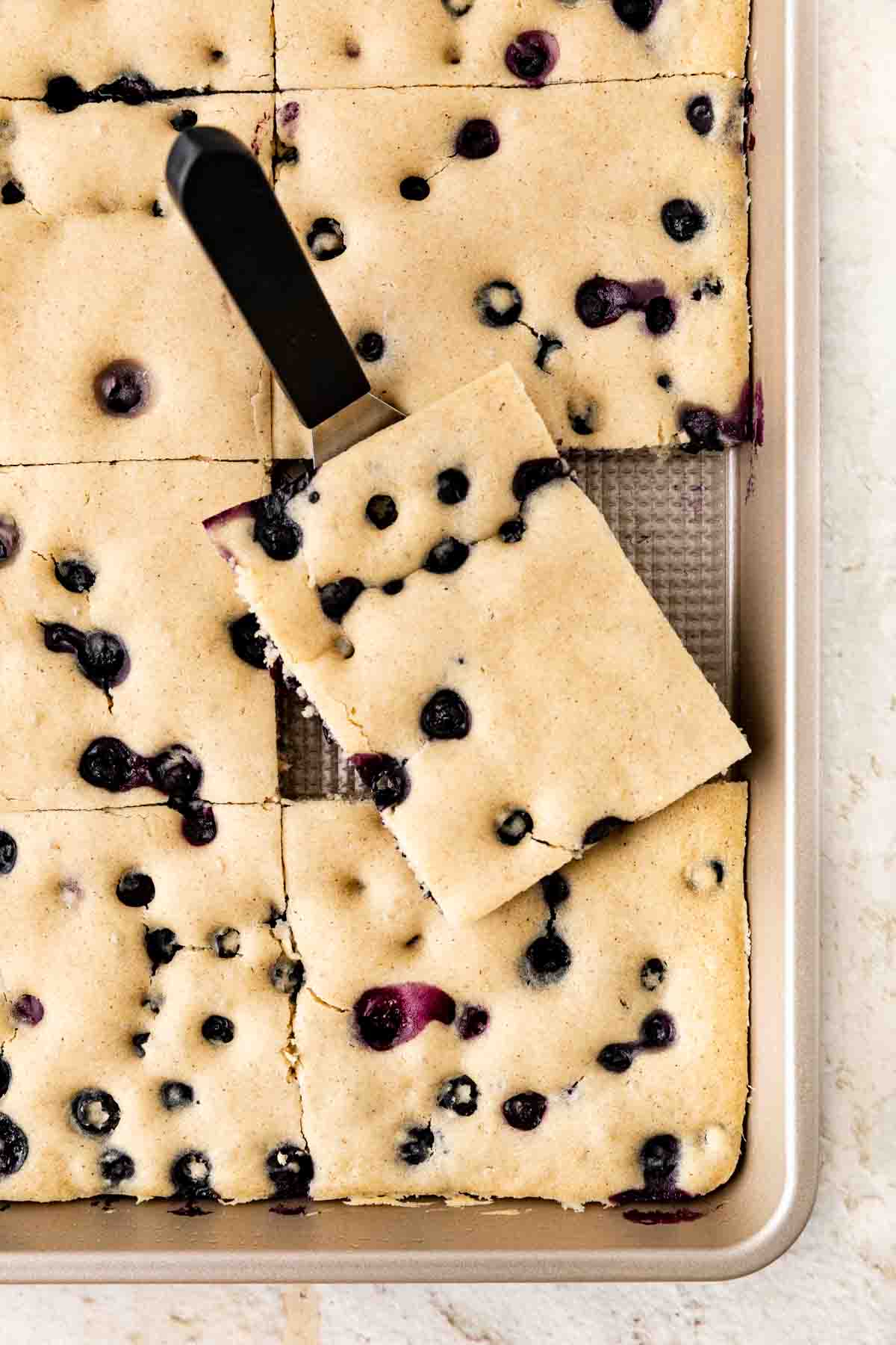 Sheet Pan Blueberry Pancakes sliced in sheet pan with spatula