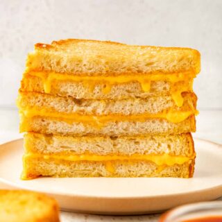 Sheet Pan Grilled Cheese Sandwiches cut in half and stacked on plate