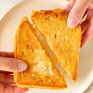 Sheet Pan Grilled Cheese Sandwiches are the easiest way to make ultimate cheesy, crispy cheese sandwiches for a crowd in less than 30 minutes! Sheet Pan Grilled Cheese sliced diagonally being pulled apart