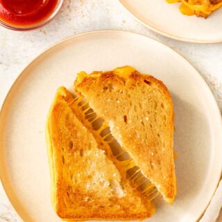 Sheet Pan Grilled Cheese Sandwiches are the easiest way to make ultimate cheesy, crispy cheese sandwiches for a crowd in less than 30 minutes! Sheet Pan Grilled Cheese sliced diagonally on plate