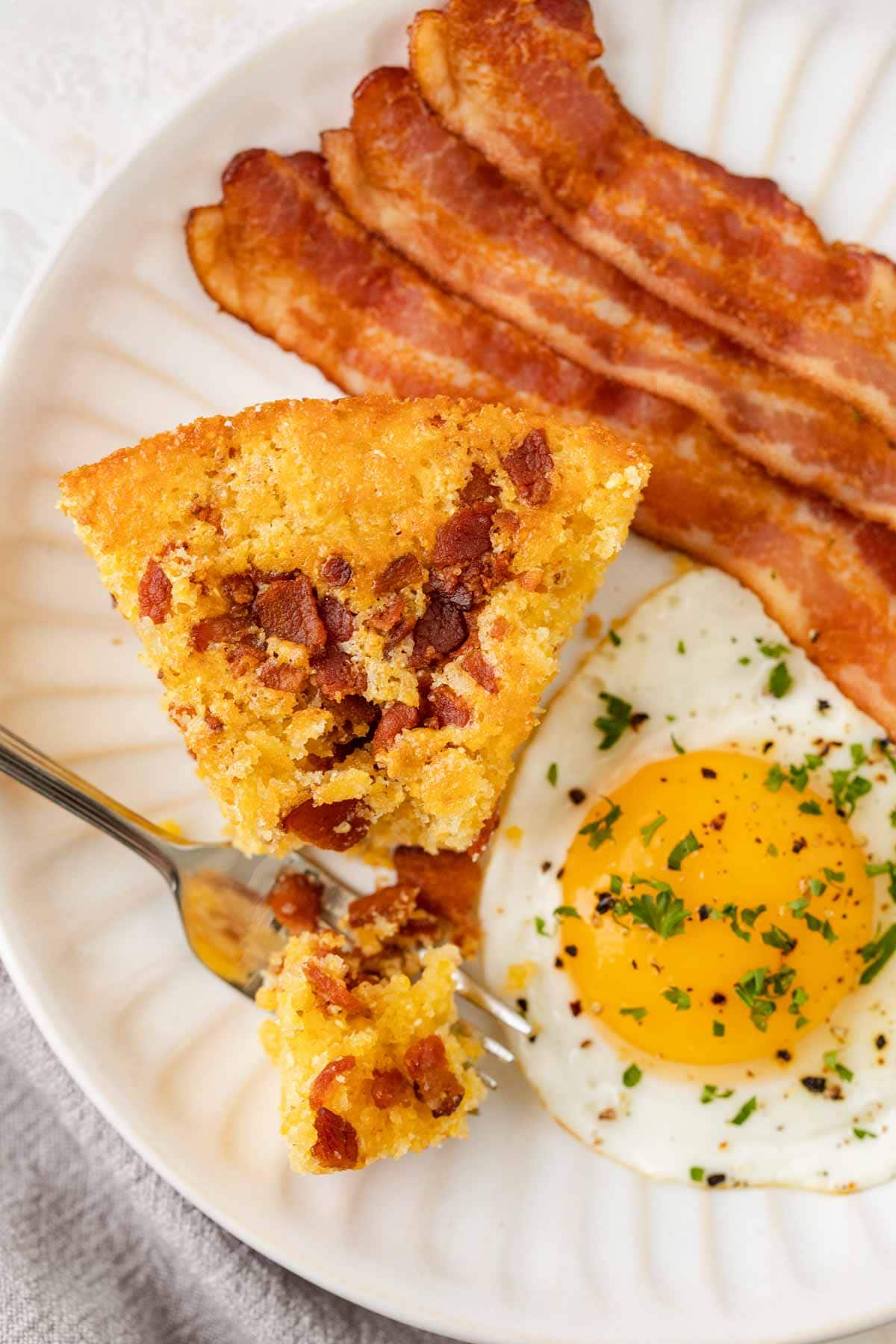 Skillet Bacon Cornbread cutting with fork on serving plate