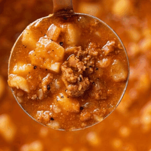 Ladle full of soup hovering over the whole pot of soup