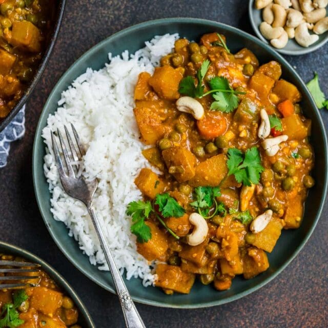 Vegetable Korma in serving bowl with cashews and cilantro garnish served over rice