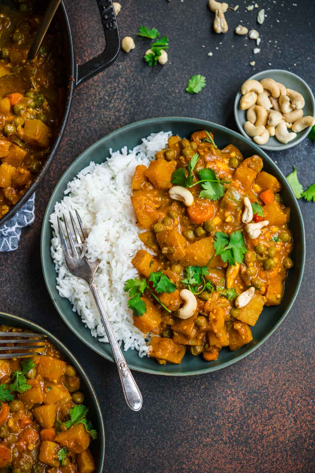 Vegetable Korma in serving bowl with cashews and cilantro garnish served over rice