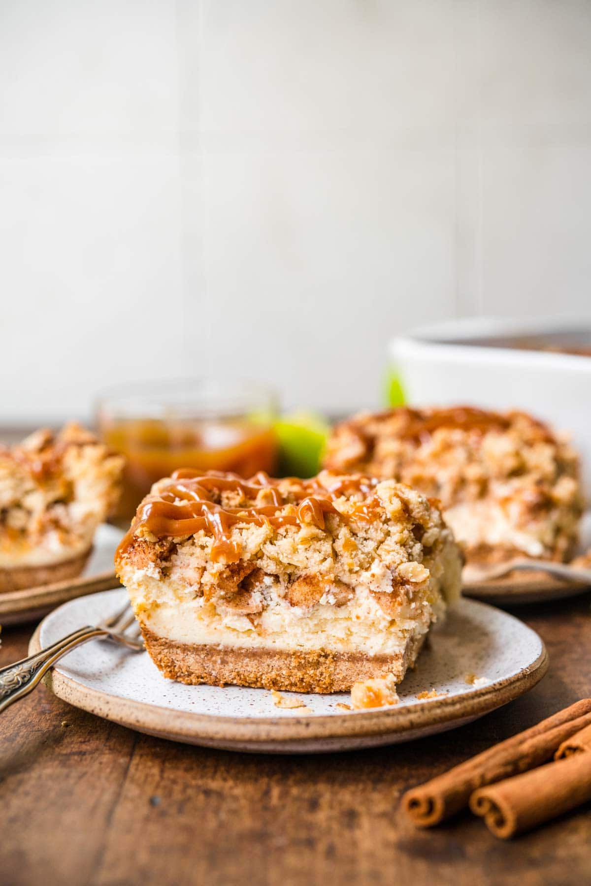 Caramel Apple Crumb Cheesecake Bars slice on plate with caramel sauce drizzled on top