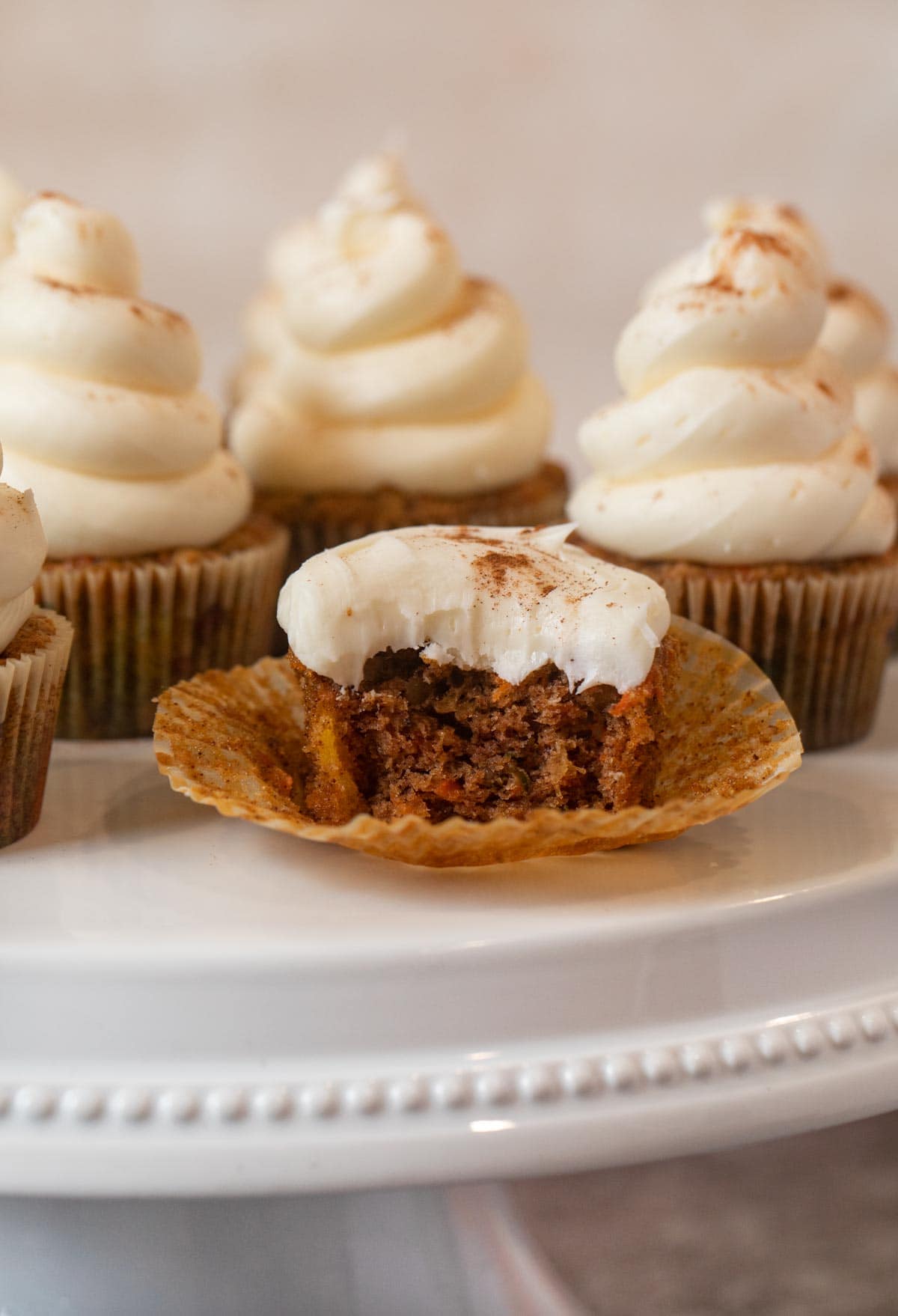 Carrot Cupcake with bite removed on cake stand