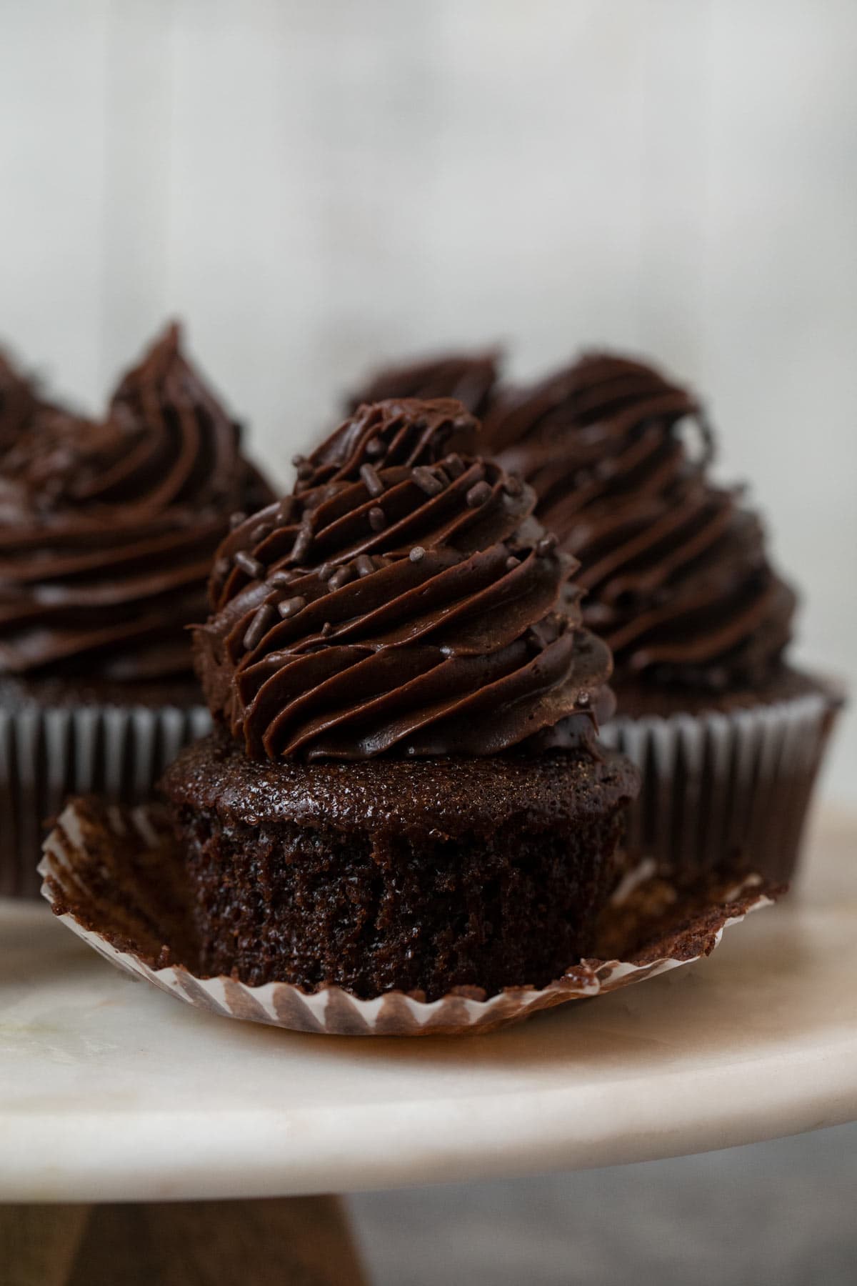 Chocolate Cupcake with Chocolate Frosting on cake stand with cupcake liner removed