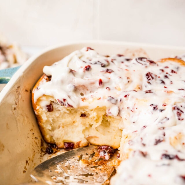 Cranberry White Chocolate Cinnamon Rolls in baking dish with icing