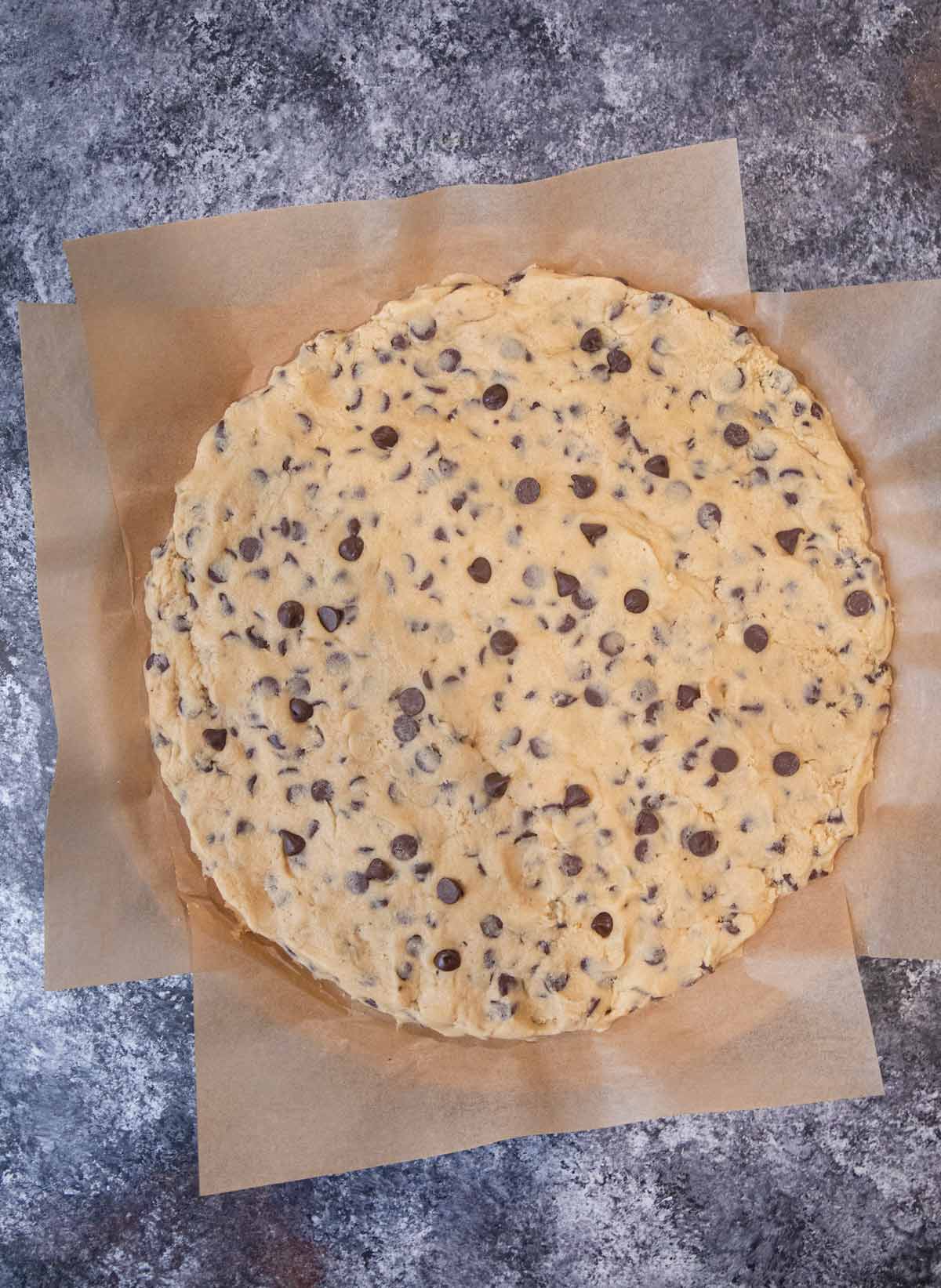 Giant Chocolate Chip Cookie dough on parchment paper