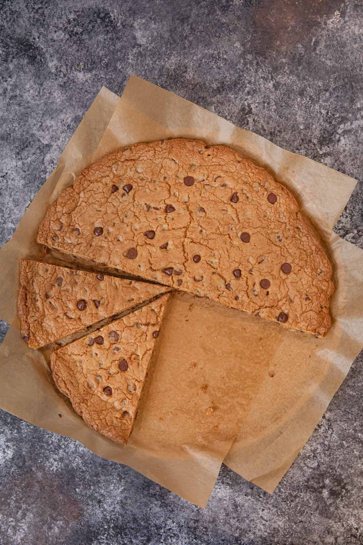 Giant Chocolate Chip Cookie sliced on parchment paper