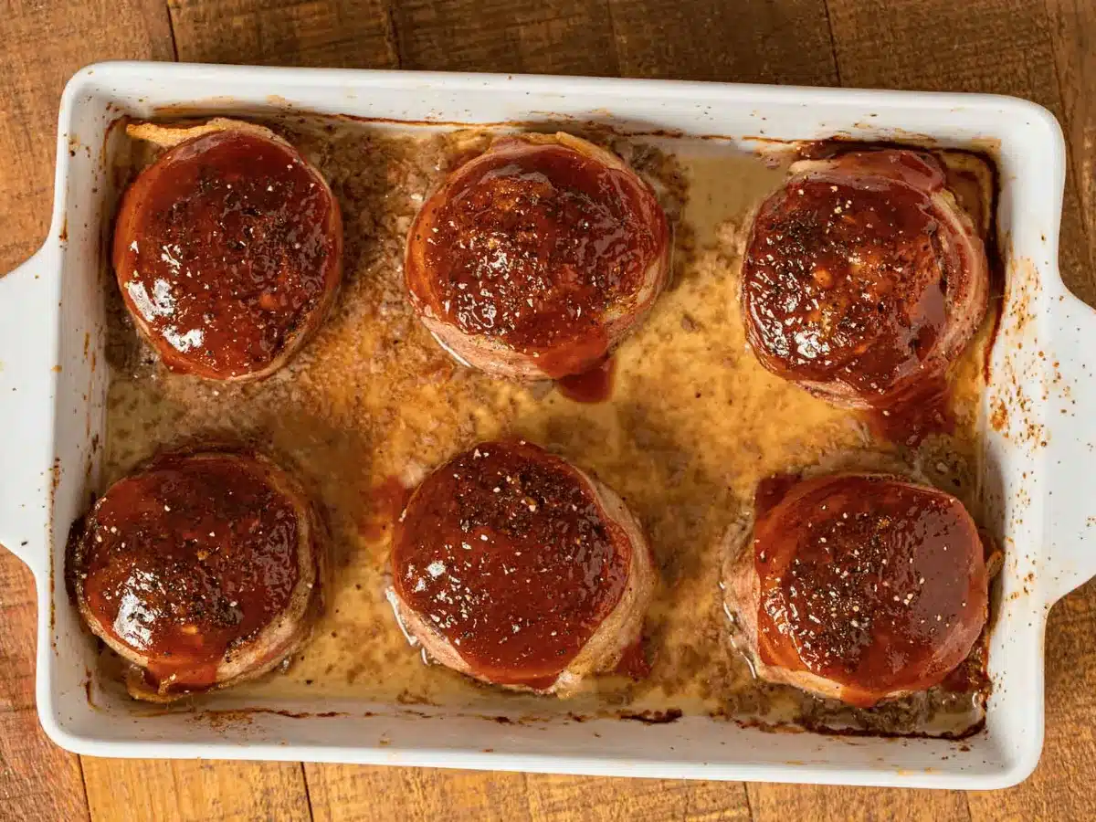 Cooked ground beef wrapped in bacon with glaze