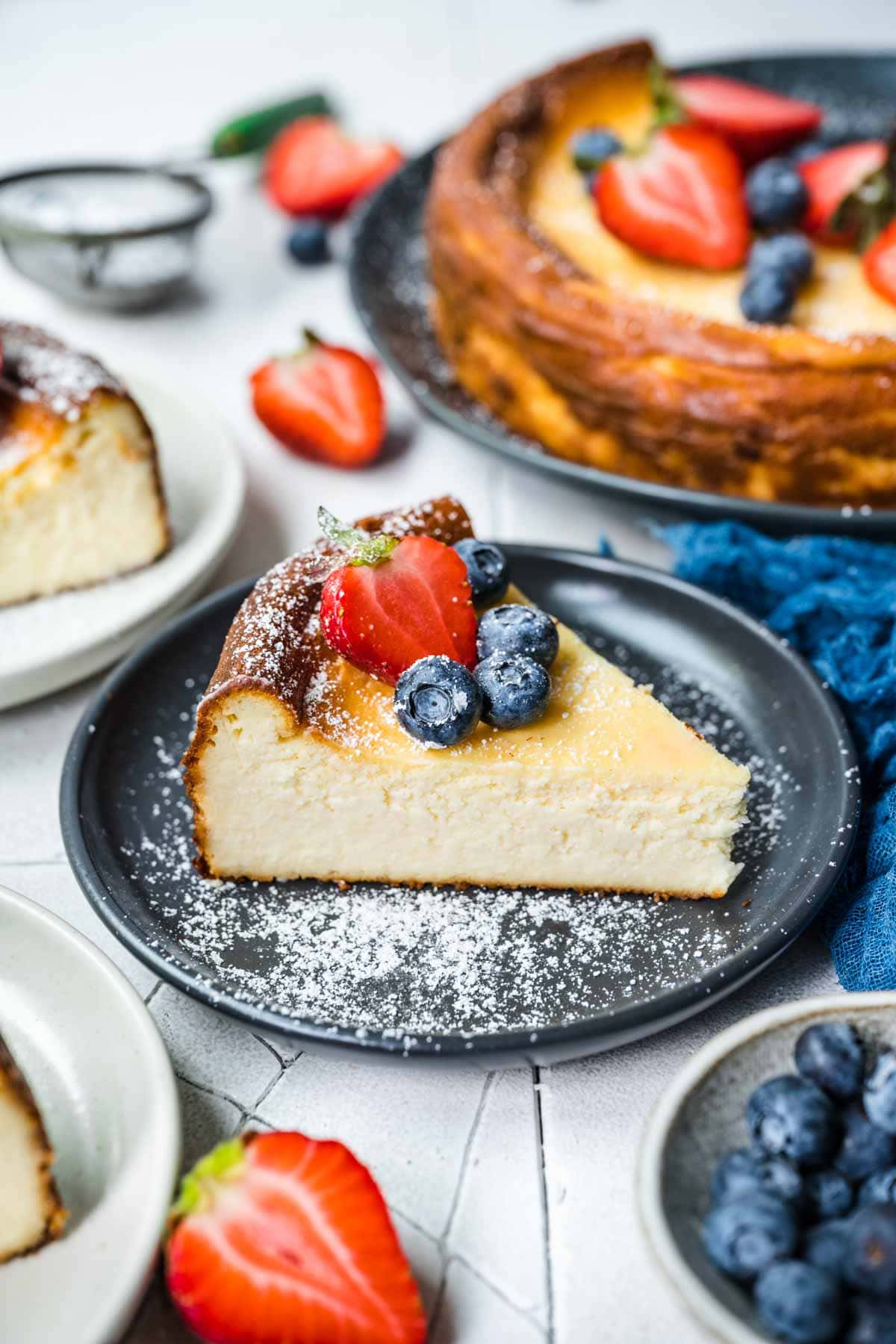 Ricotta Cheesecake slice on serving plate with fresh berries and powdered sugar on top