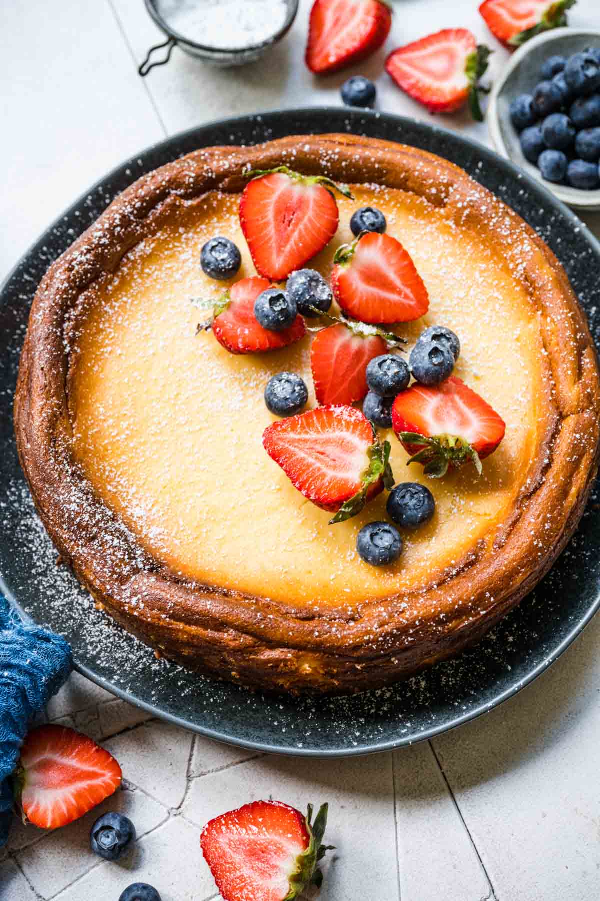 Ricotta Cheesecake on serving plate with fresh berries and powdered sugar on top