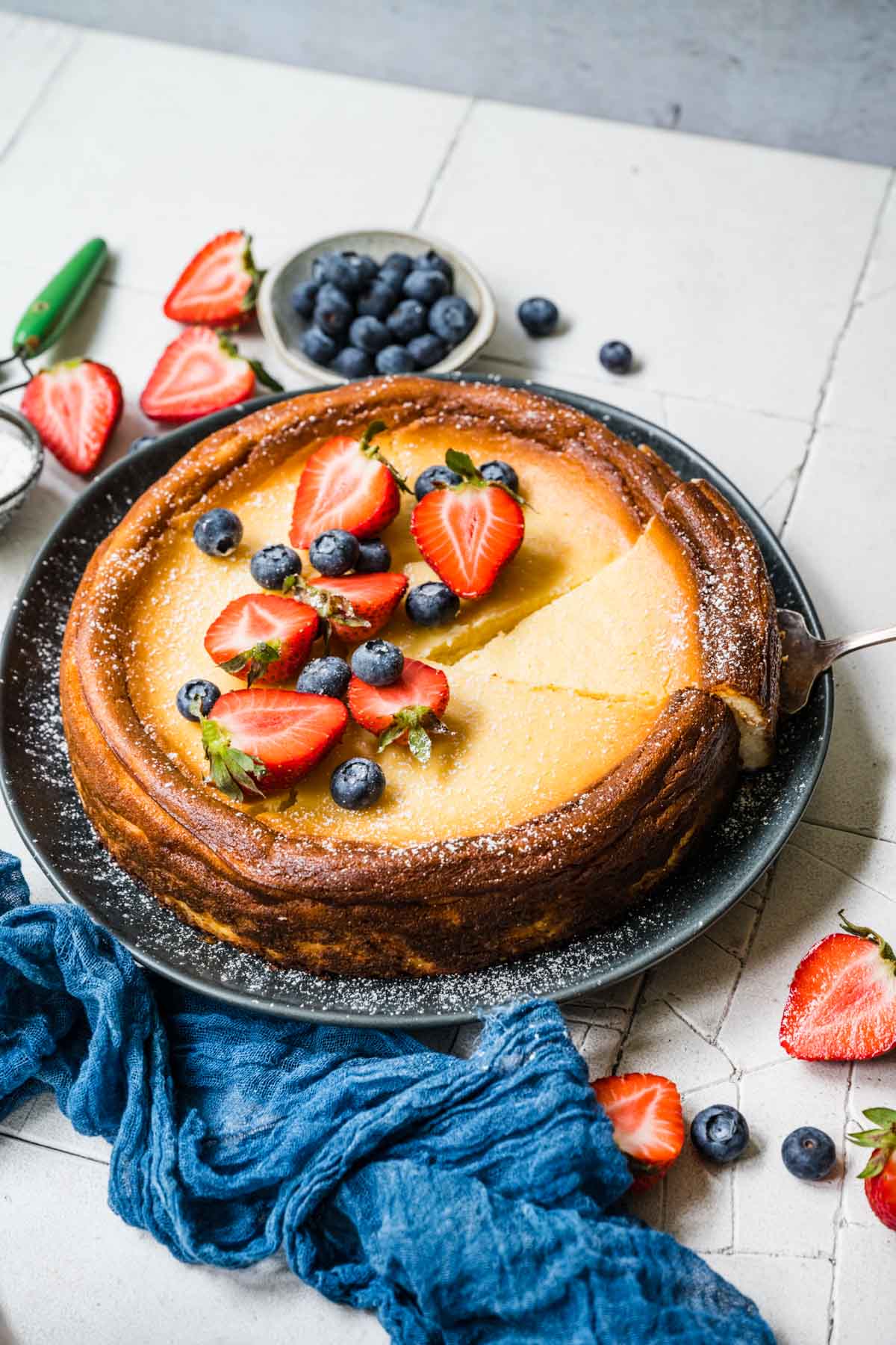 Ricotta Cream Cheese Cheesecake on serving plate with fresh berries and powdered sugar on top