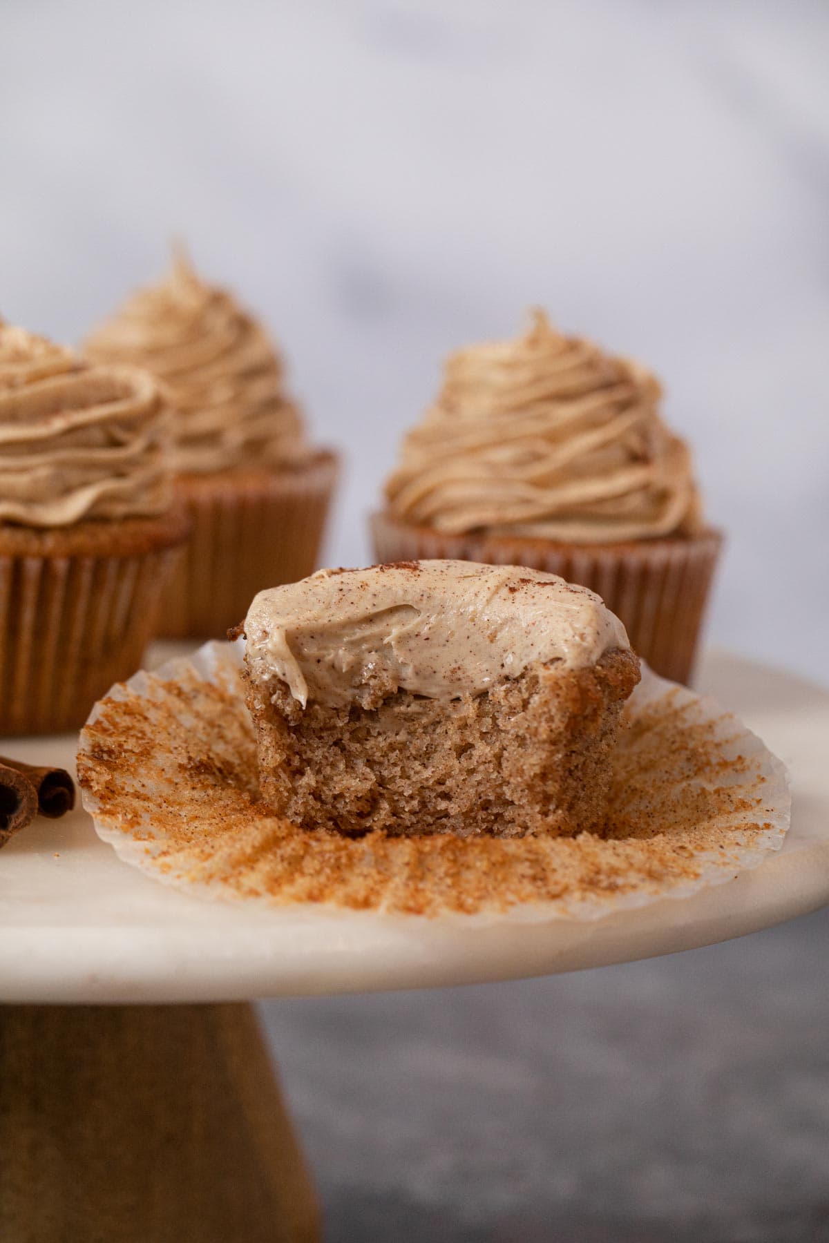 Snickerdoodle Cupcakes with bite removed on cake stand