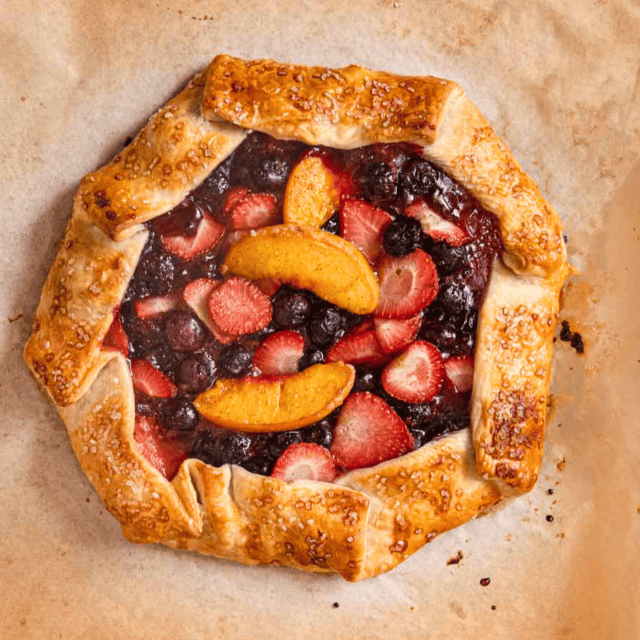 Baked fruit and berry galette on parchment paper.
