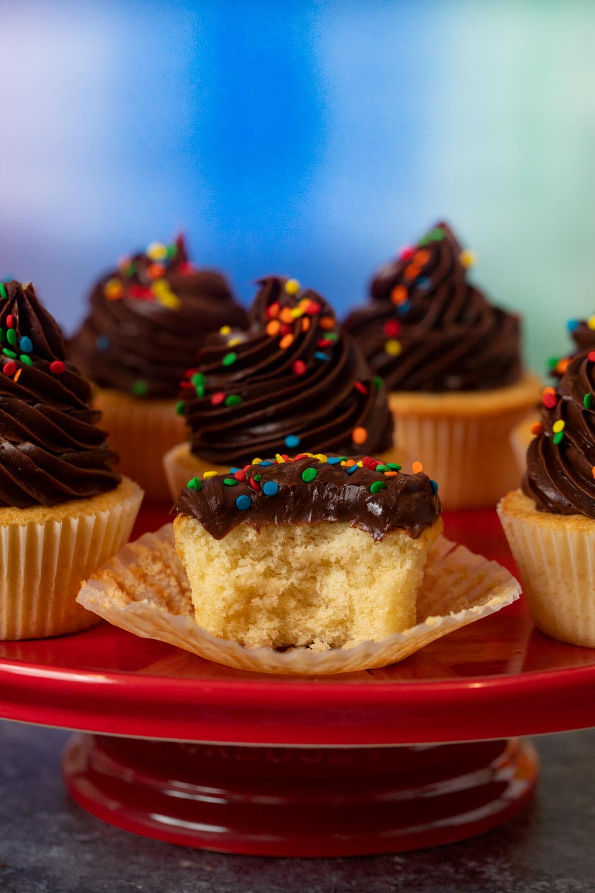 Yellow Cupcakes with Chocolate Frosting with rainbow sprinkles on cake stand