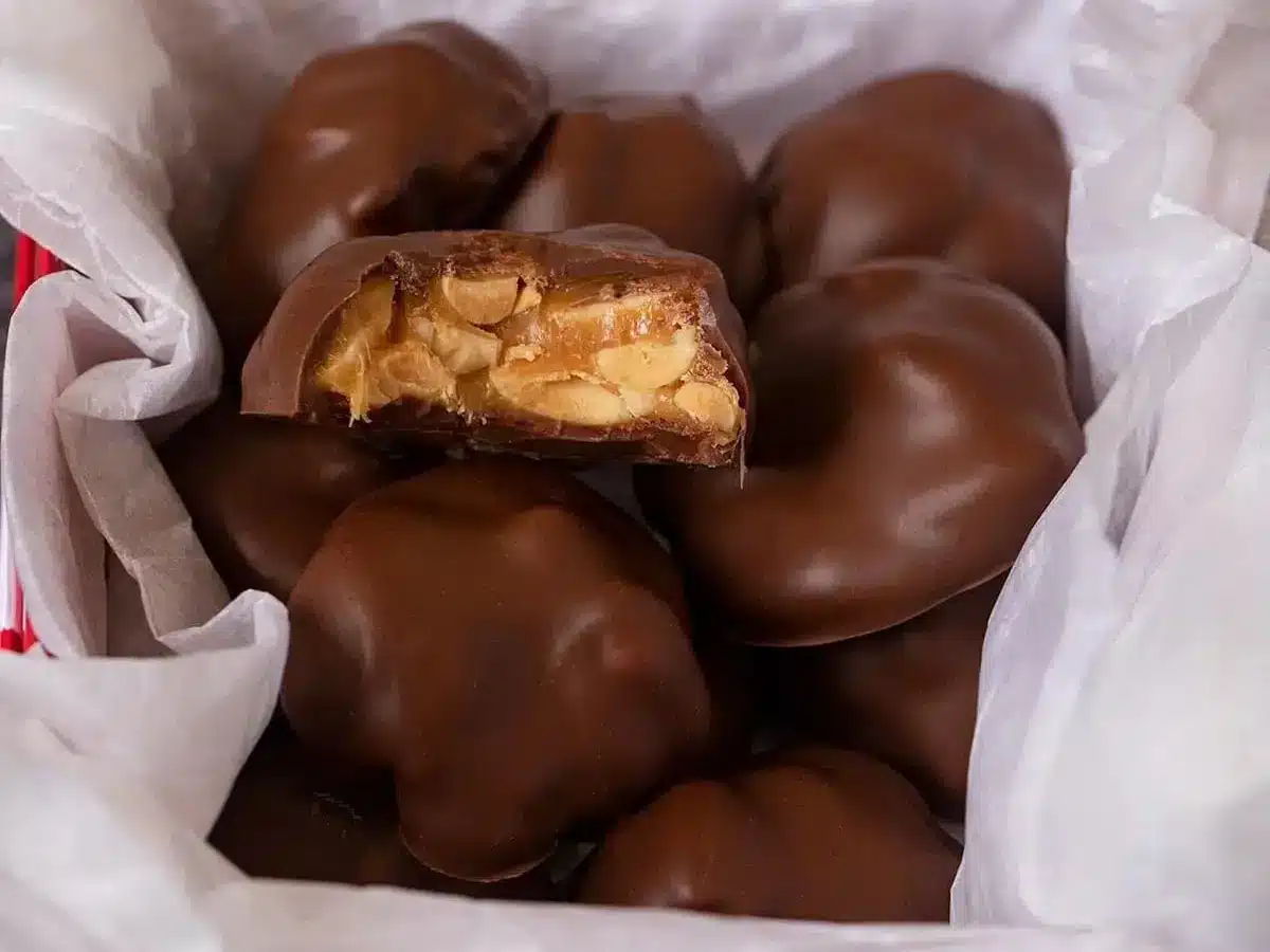 chocolates in a box with tissue paper and a bite taken out of one chocolate
