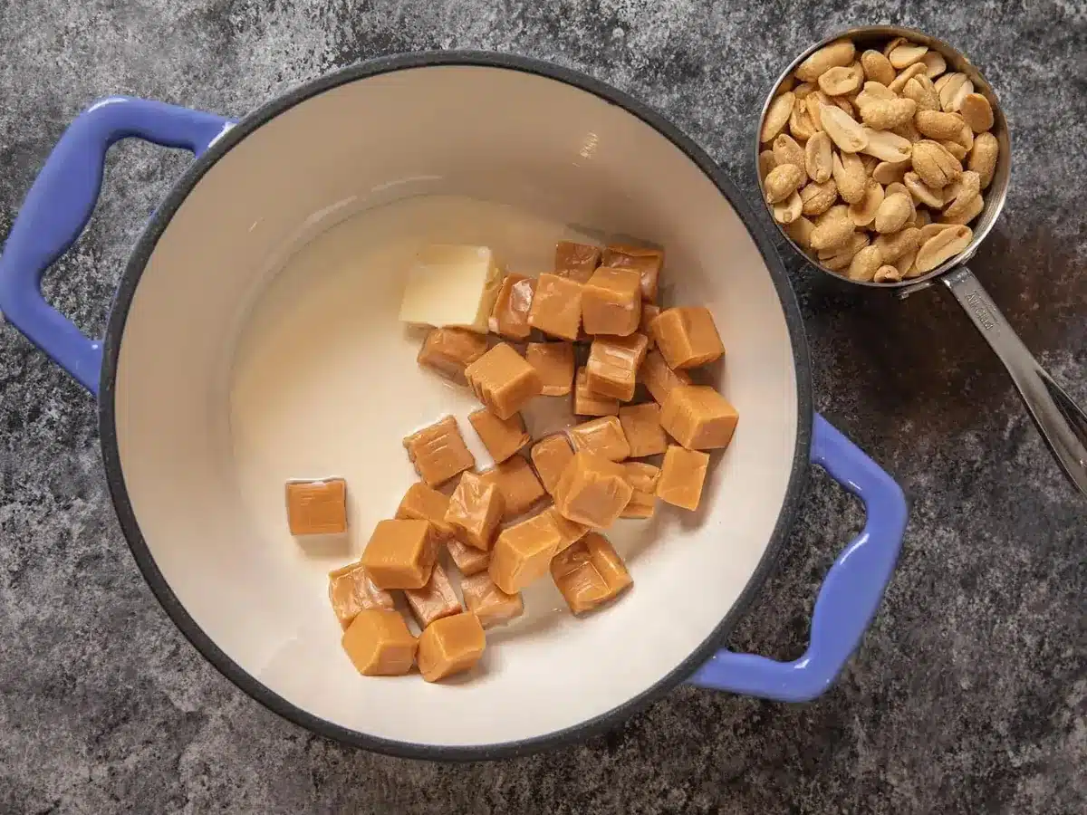 caramel and butter in a pot with peanuts in a measuring cup next to it