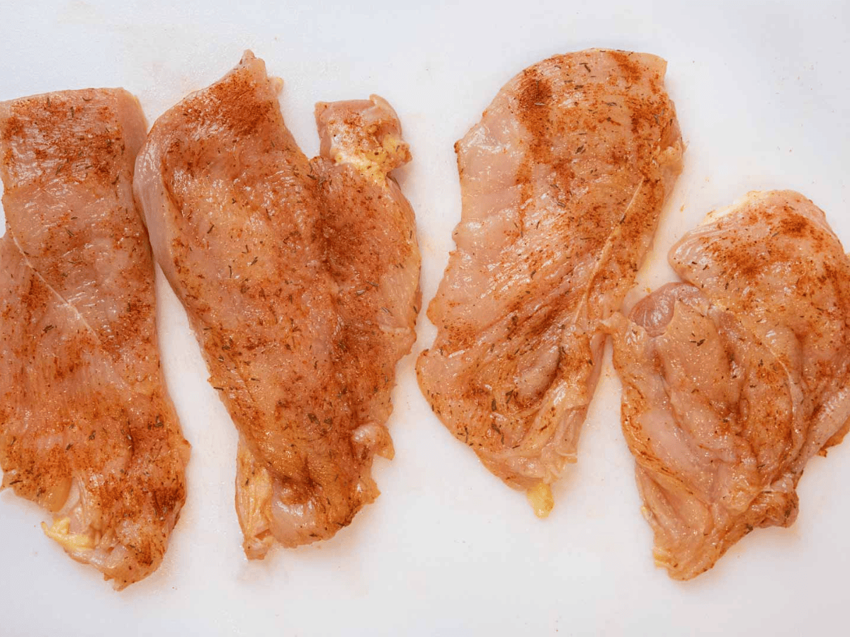 raw chicken with seasonings sprinkled on top