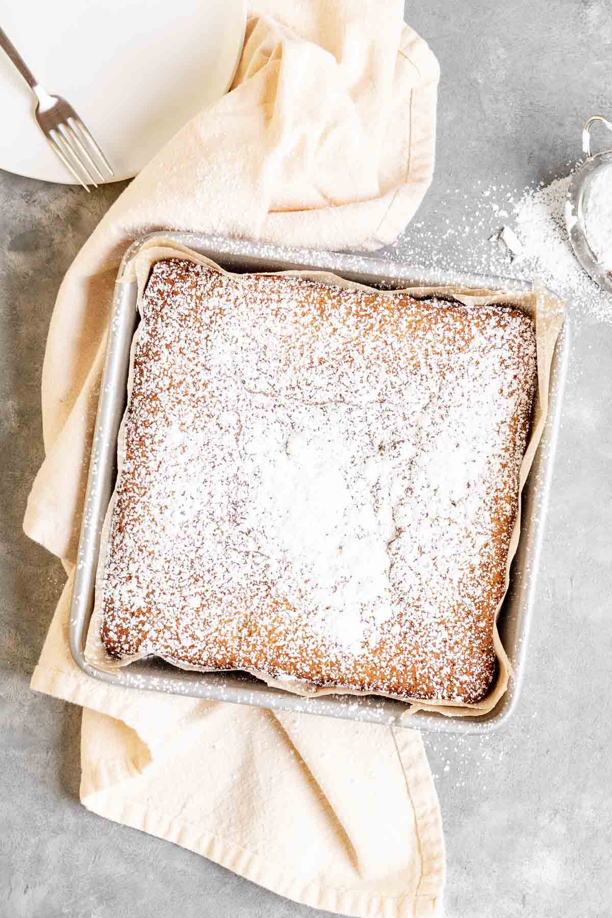 Butter Cake in 8x8 baking pan after baking with powdered sugar dusted