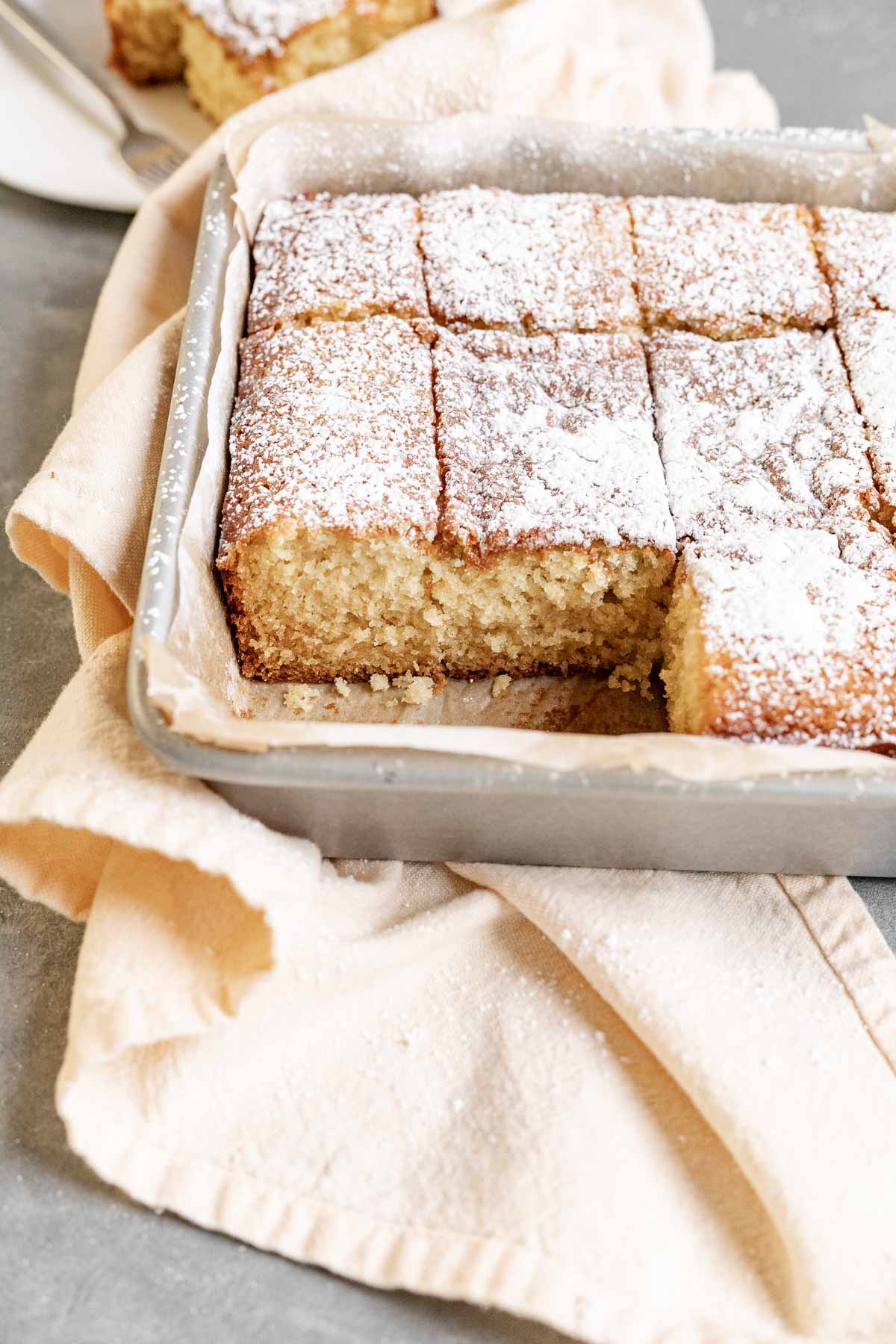 Butter Cake dusted with powdered sugar sliced in baking pan