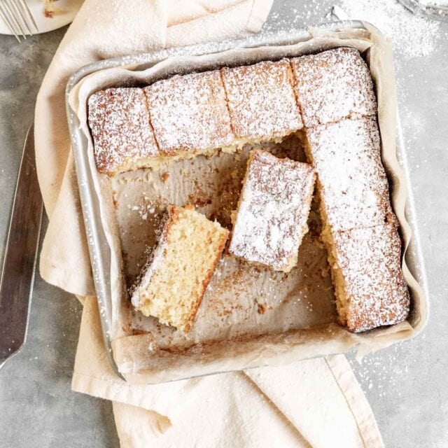 Butter Cake dusted with powdered sugar sliced in baking pan